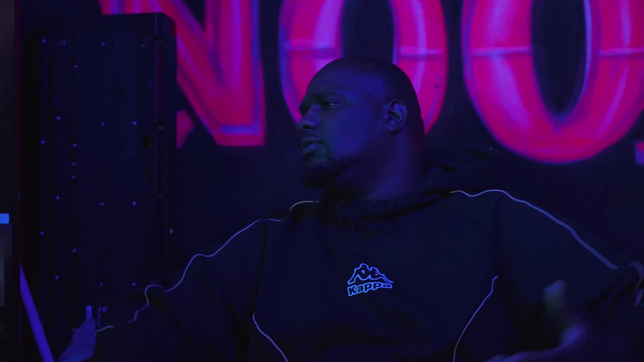 Man in een donkere ruimte onder roze neonlicht